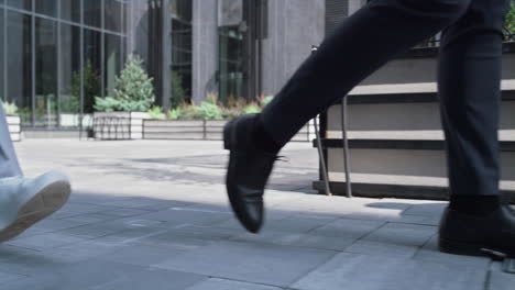 confident manager walking downtown district on lunch break. male legs closeup.