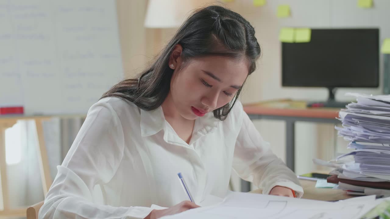 사무실에서 문서와 함께 일하는 동안 종이에 무언가를 쓰는 아시아 여성의 클로즈업