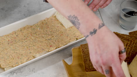 Sliding-shot-of-a-chef-placing-the-top-pieces-of-bread-onto-the-sandwich-to-complete-the-dish