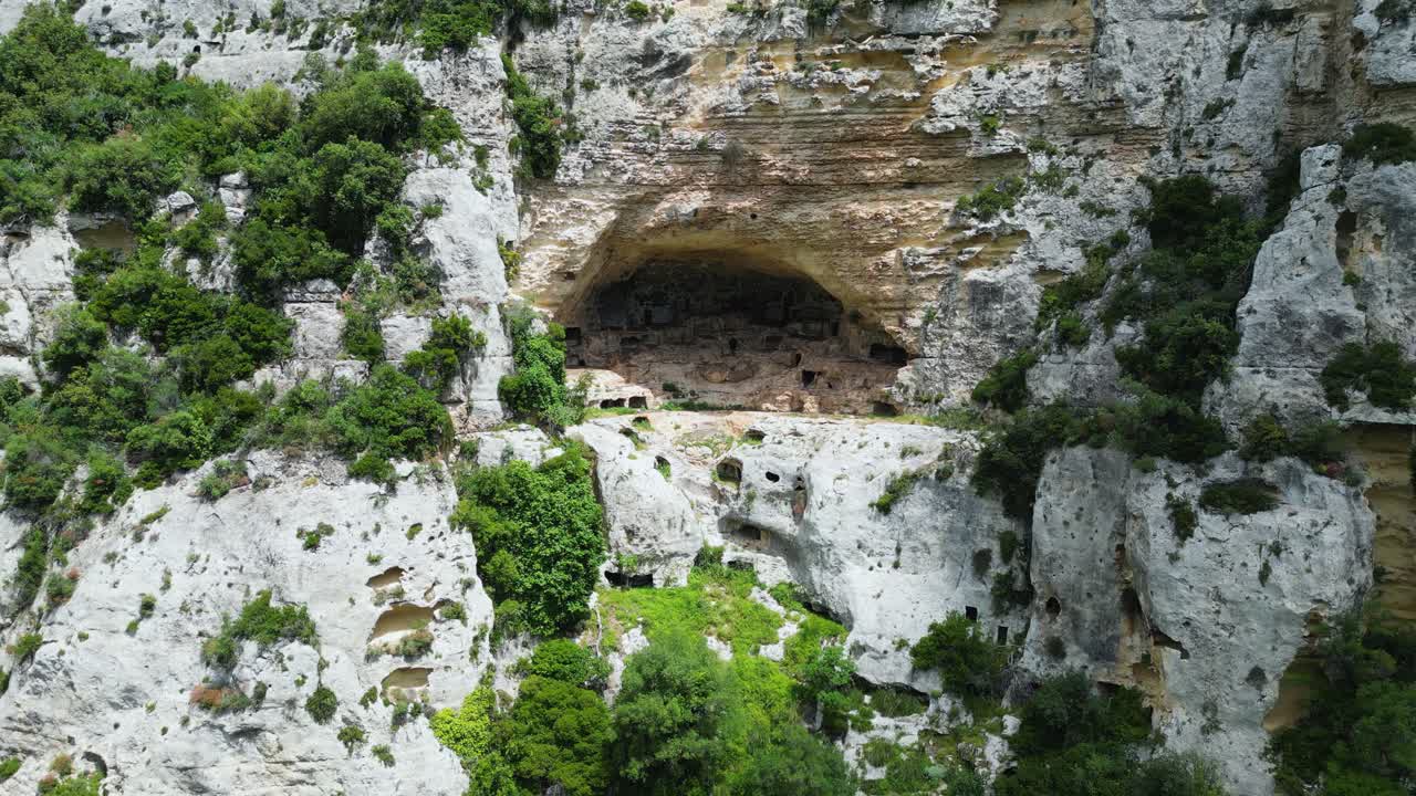 Aerial drone footage of Cava del Cassibile, Sicily: deep canyon with turquoise river, rocky cliffs, and lush nature. Perfect for travel, adventure, and nature documentary projects