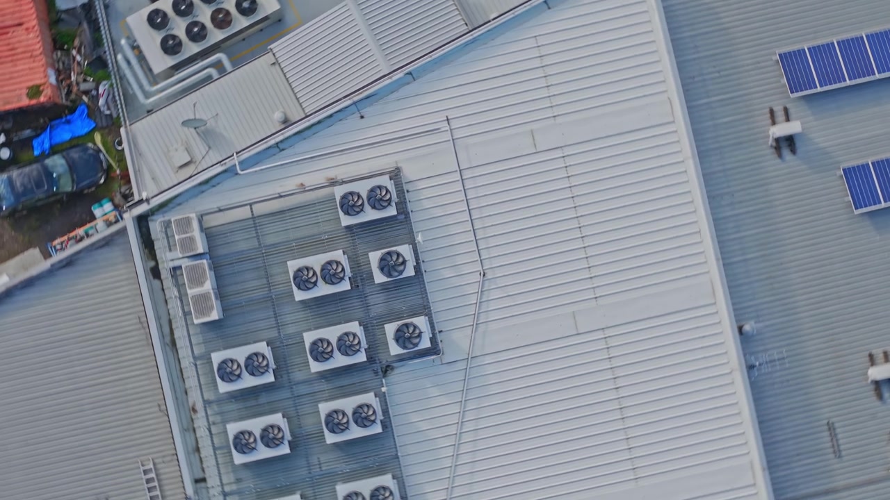 Drone video captures a wide, detailed rooftop of data center featuring numerous industrial HVAC units, solar panels, and clean modern roofing ideal for technology, infrastructure, or business themes.