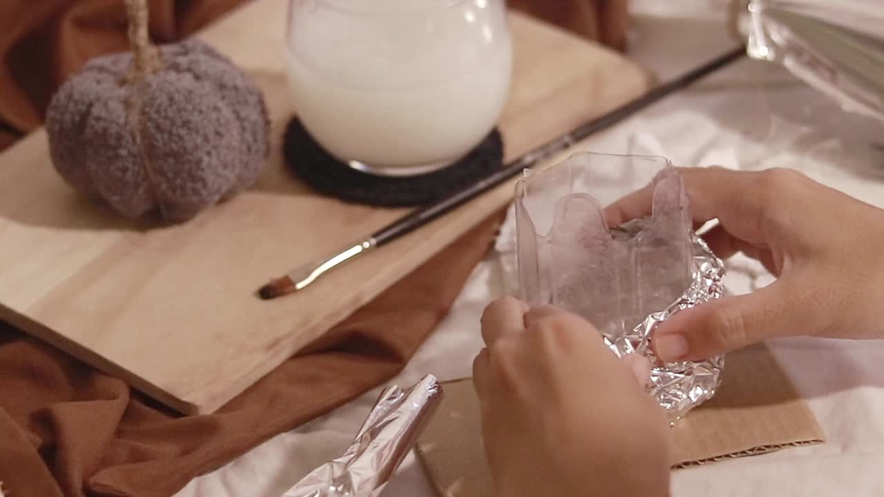 Shaping tin foil around a cut plastic bottle, creating a rabbit shape mold in an Easter theme DIY recycling craft project