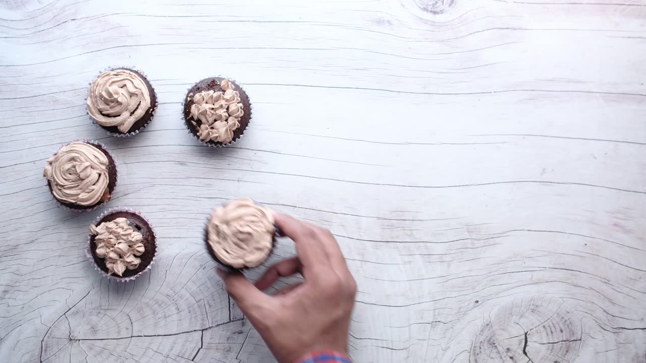 나무 테이블 에 있는 초콜릿 컵케이크 를 잡는 손
