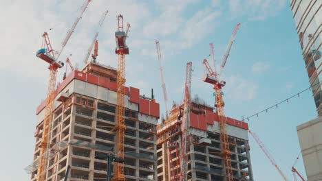 desarrollo de la construcción de grúas de la torre de apartamentos residenciales sin terminar en construcción cielo azul
