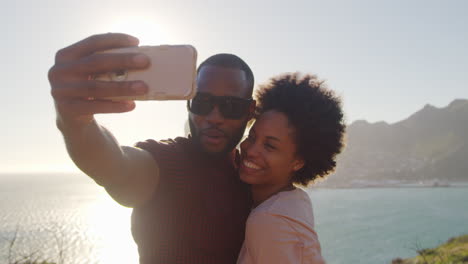 young couple pose for holiday selfie on clifftop