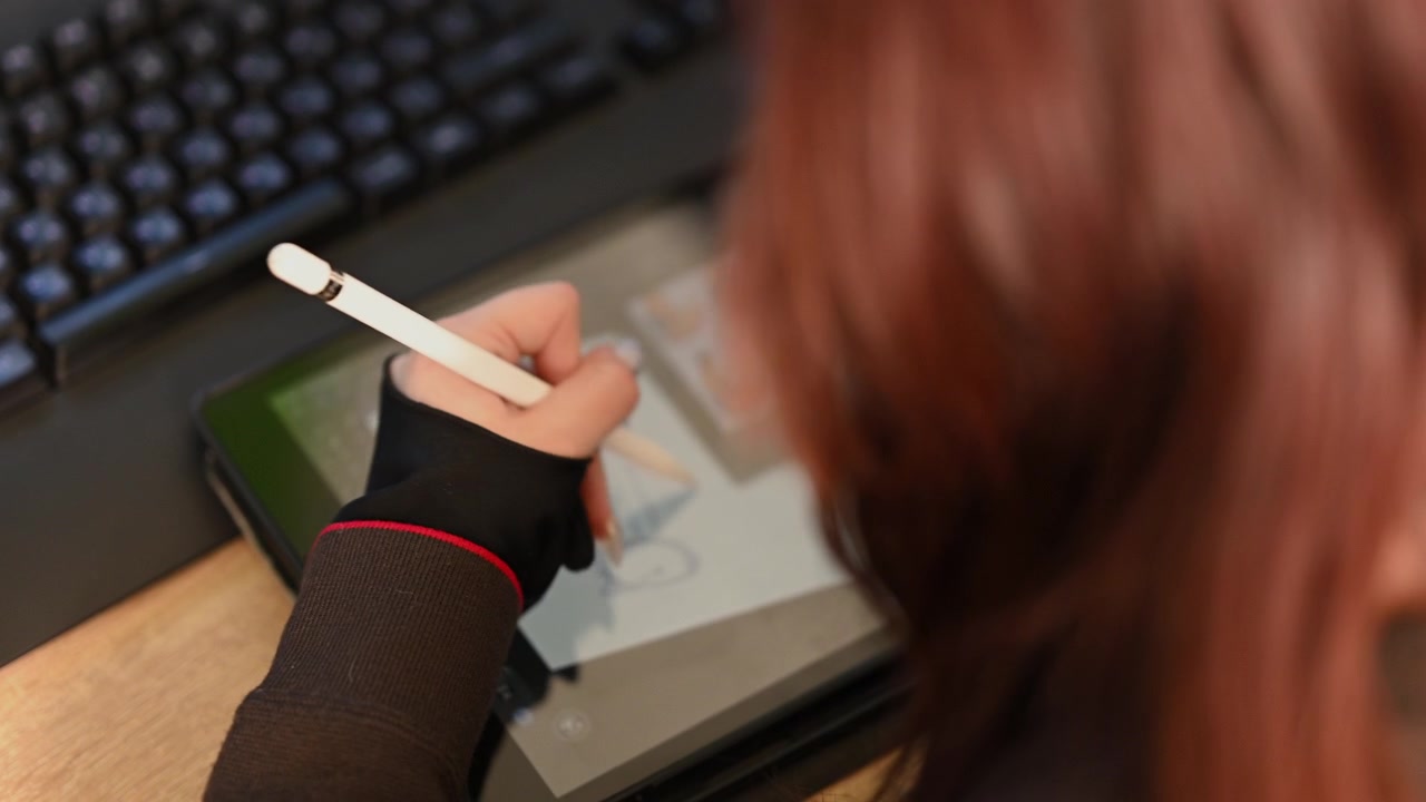 Close up of a student using a white stylus to draw a simple character sketch on a digital drawing tablet