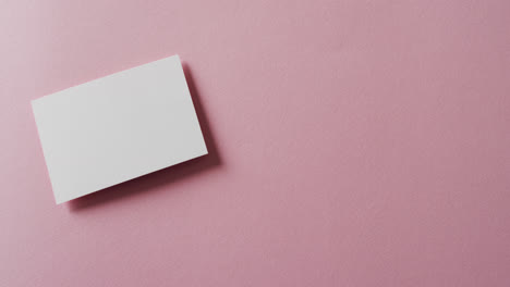 blank white business card on pink background, copy space, slow motion