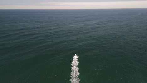 following shot of motorboat speed by on the ocean waves
