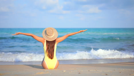 foto trasera de una mujer en forma extendiendo los brazos en el fondo del paisaje marino de la playa