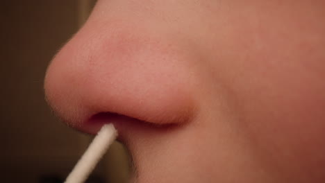 close-up of a child's nose being swabbed for a covid-19 at home rapid antigen test