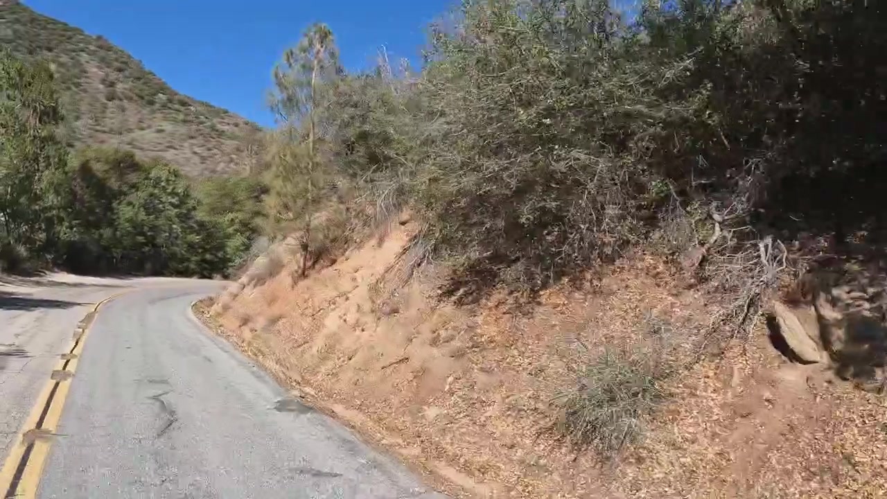 Vista dinámica desde el conductor en una pintoresca y sinuosa carretera de montaña en un valle rústico.