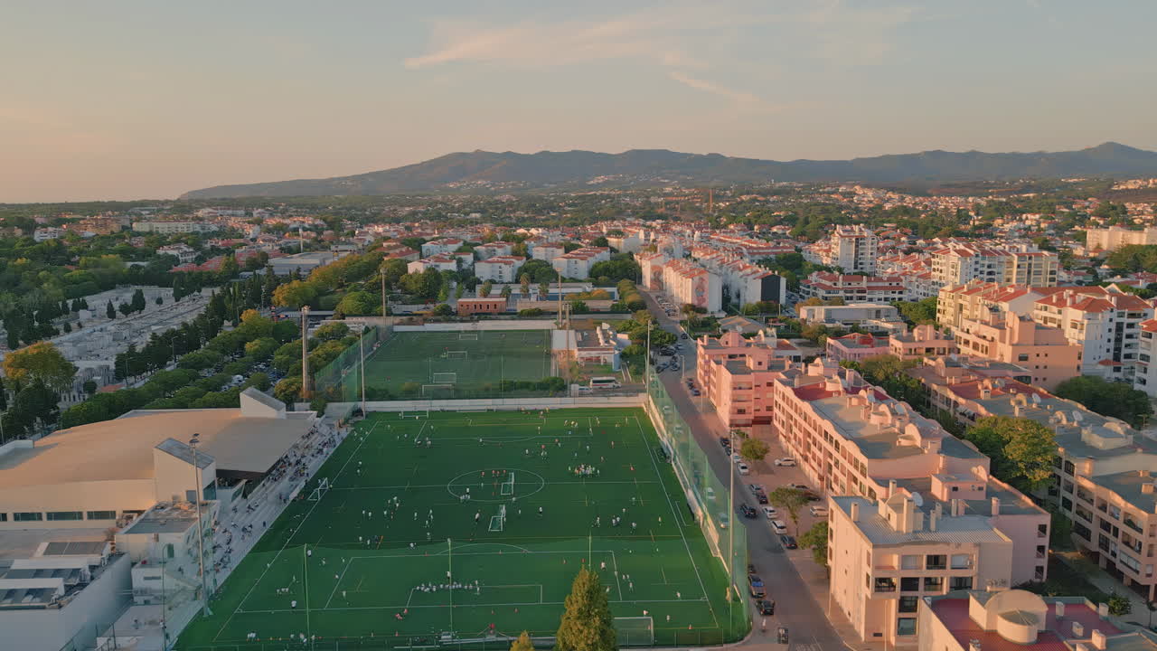 Aerial calm evening cityscape with mountains background. Green football stadium