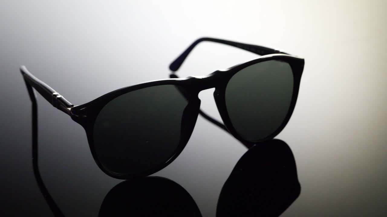 un par de costosas gafas de sol de aviador de lujo con lentes polarizadas sobre un fondo blanco y negro con reflejo