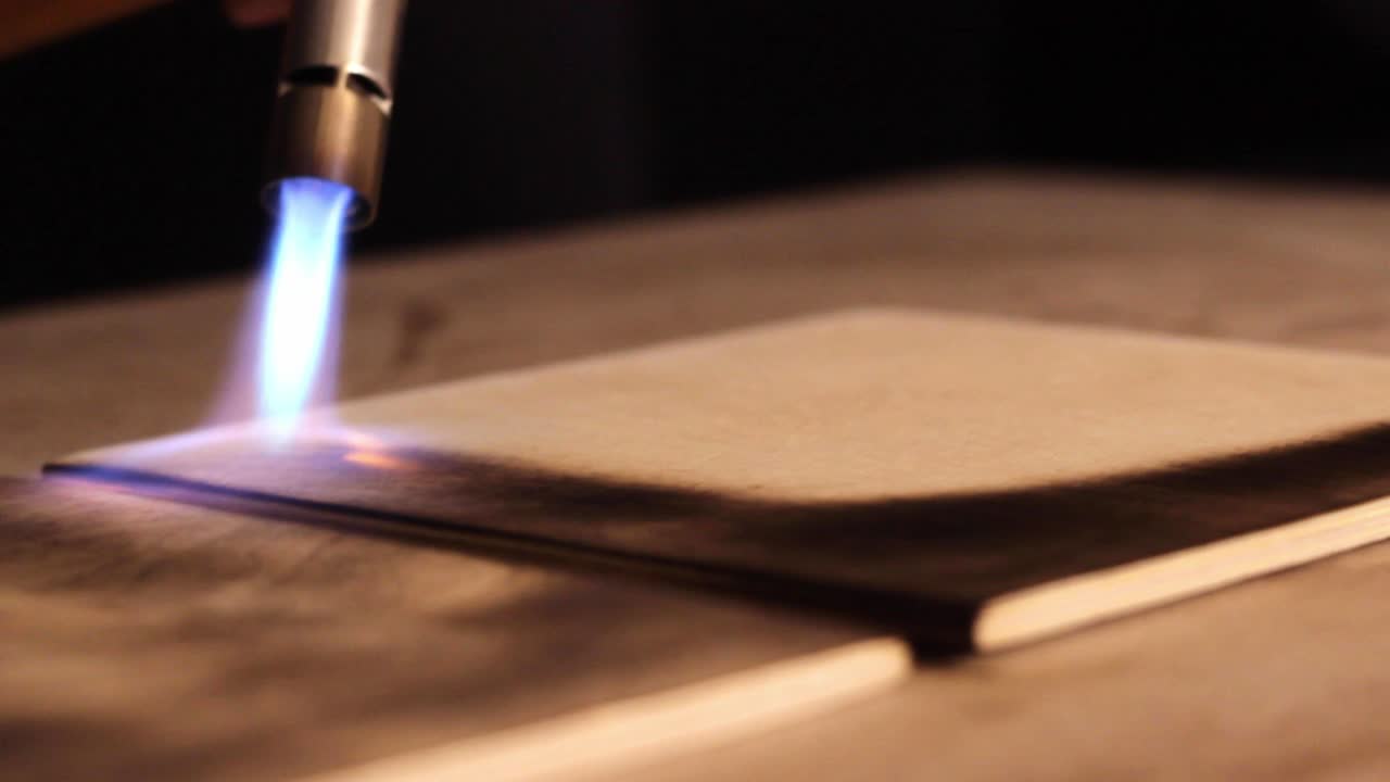 cerca de usar una antorcha para terminar paneles de madera cuadrada, quemándolos y haciéndolos oscuros