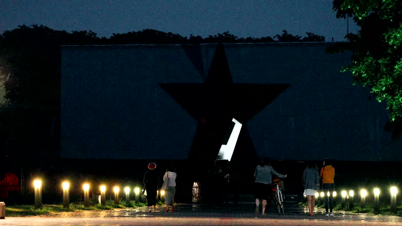 브레스트, 벨라루스: 브레스트 요새의 주요 출입문 근처에서 걸어가는 사람들, 브레스트 영웅 요새의 기념 복합 건물, 저녁 밤의 조명