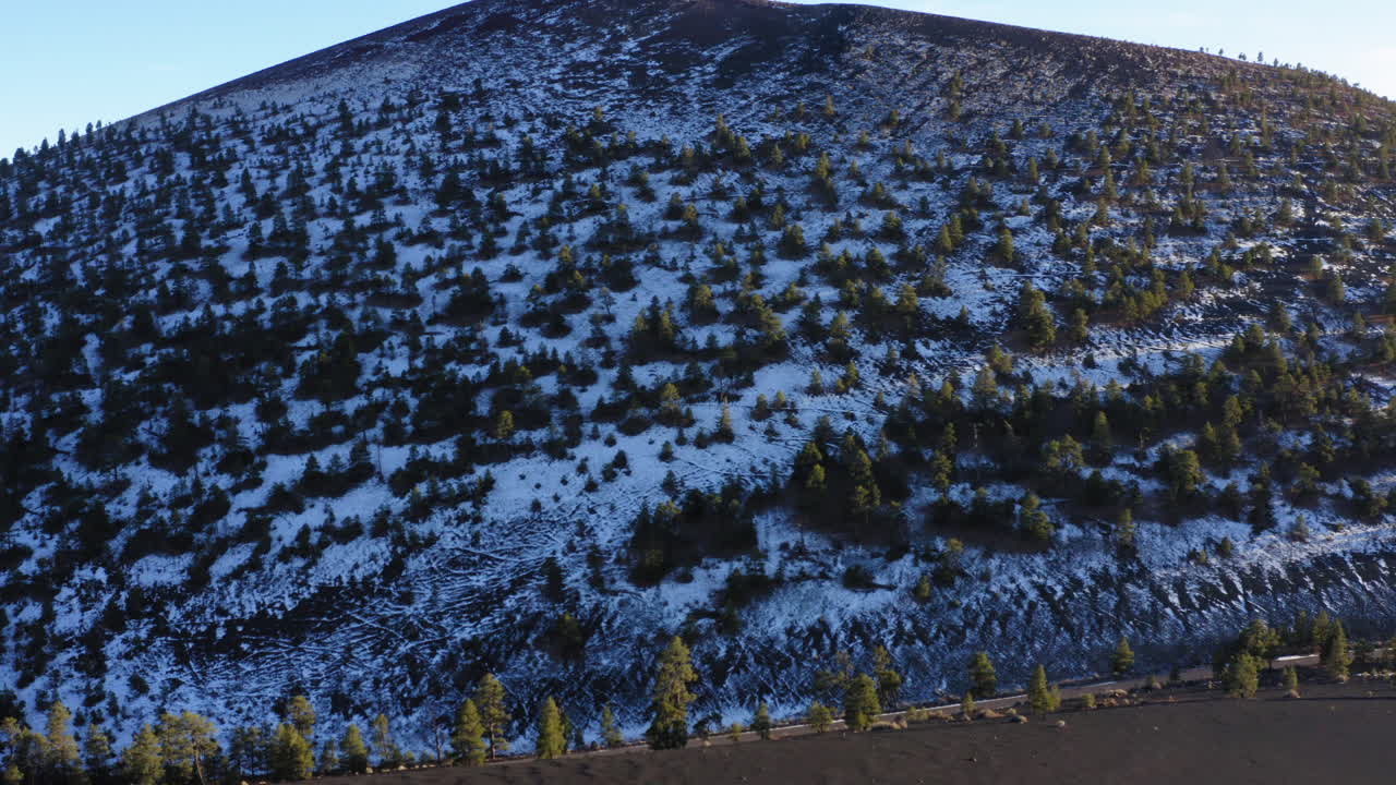 항공:일몰 분화구에 소나무가 있는 눈 덮힌 산, 깃대 - 드론 후방 촬영