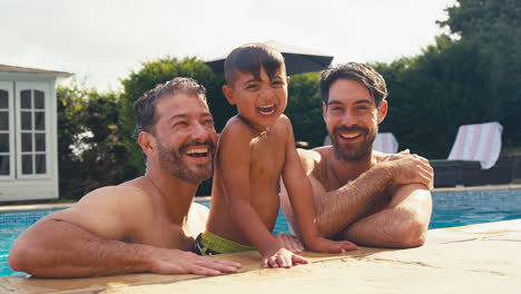 Retrato-De-Una-Familia-Del-Mismo-Sexo-Con-Dos-Padres-Y-Un-Hijo-De-Vacaciones-Juntos-En-La-Piscina