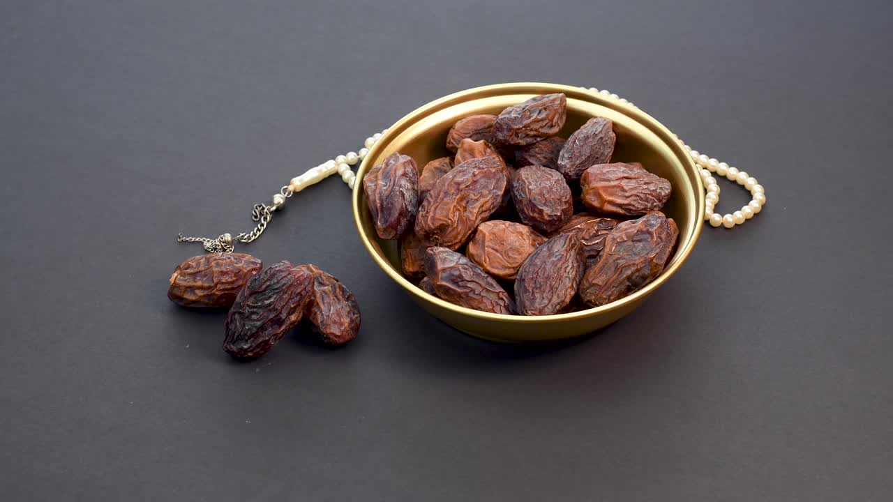 Date Fruit and Rosary on Black Background. Rotating on Turn Table. Iftar Food Mostly Eating in Ramadan. 4K Resolution.