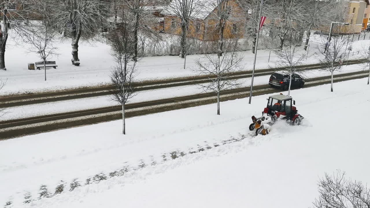 Tractor clean snow from walkway with plough sweeping brush