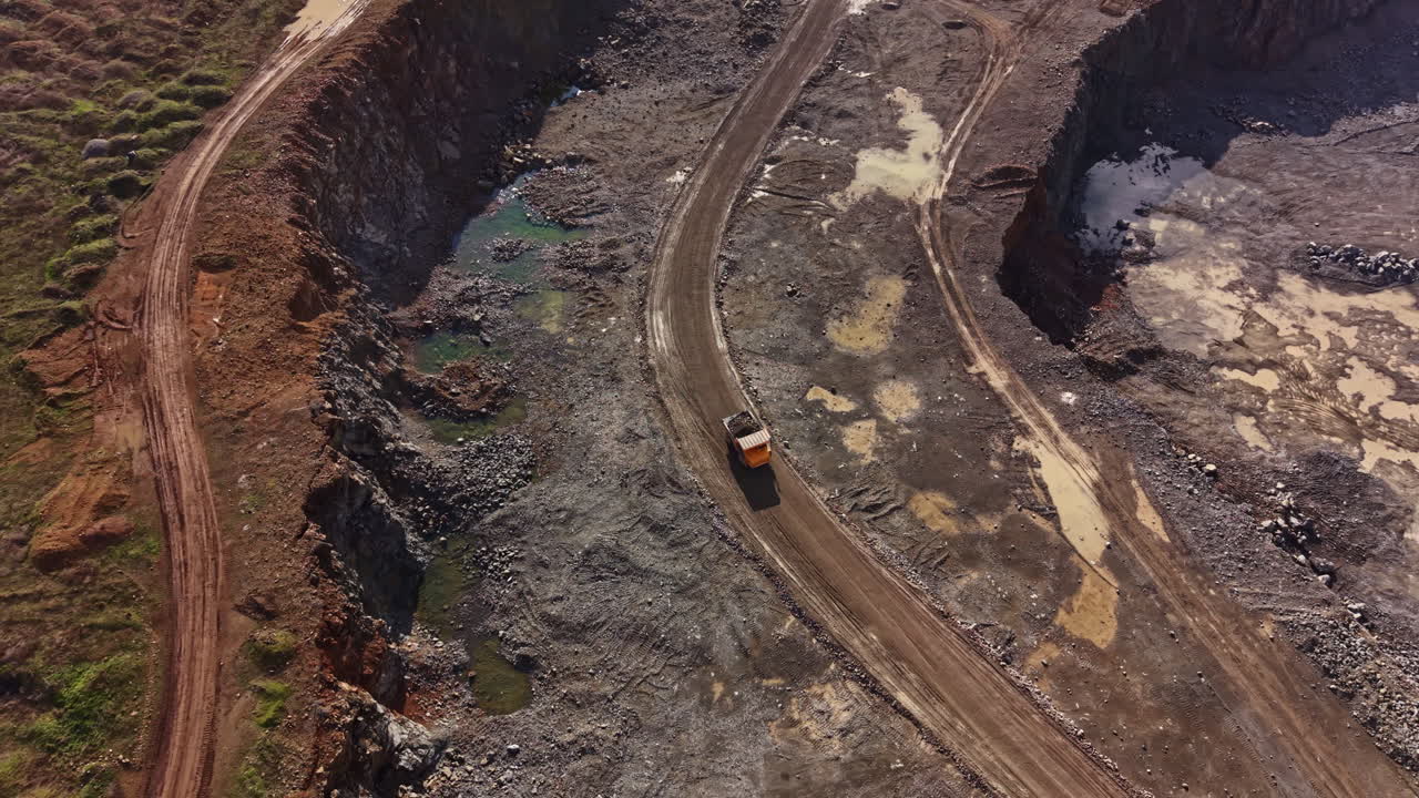 Granite quarry operation during daytime showing trucks and extraction activities in an active mining site