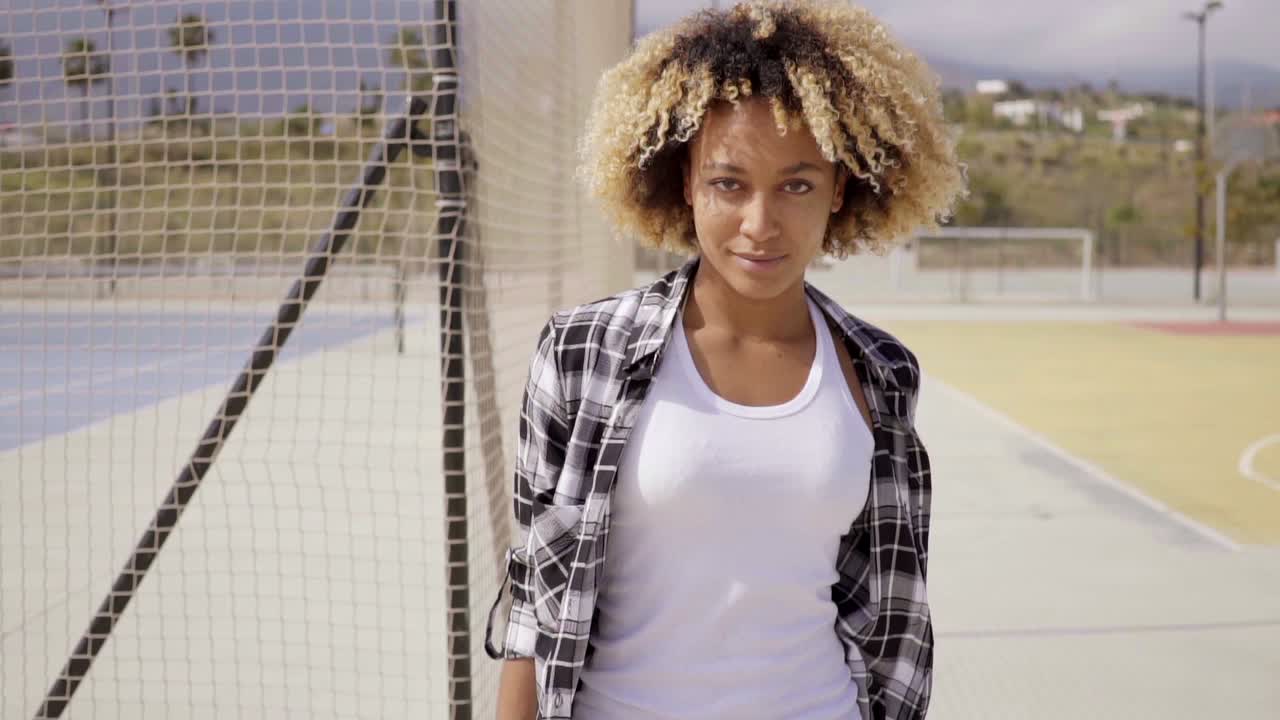 mujer joven con poses de monopatín por cancha de pelota