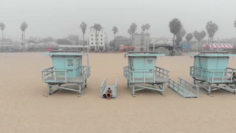 Volando-Entre-Dos-Puestos-De-Salvavidas-En-Venice-Beach,-Ca-En-Una-Gruesa-Capa-Marina