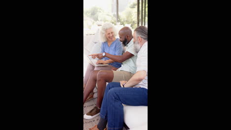 vertical video: seniors sitting on couch, using laptop and discussing something together