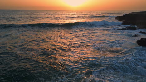 stormy sea breaking cliffs at sunset drone view. ocean waves crashing stones