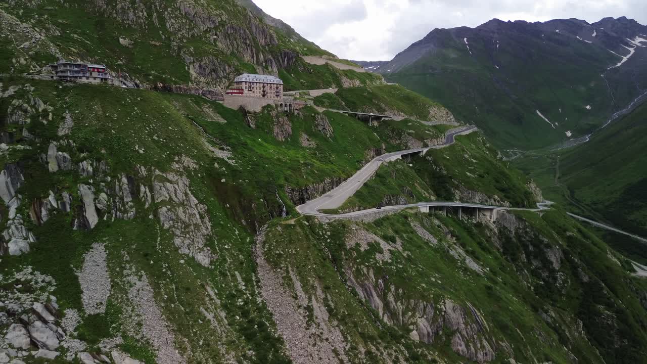 Furka Pass in Switzerland during cloudy day with low traffic and iconic hotel shot from a drone