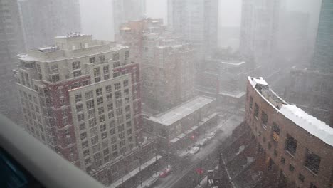 high vantage point view of a robson street in city of vancouver canada during a white strong snow storm blizzard blowing sideways surrounded by big buildings and skyscrapers