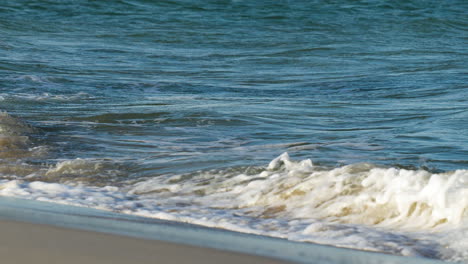Sanfte-Wellen-Im-Meer-Mit-Einem-Blick-Auf-Den-Sandboden-Durch-Klares-Wasser