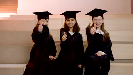 zoom in of happy kindergarten students in cap and gown looking at the camera and doing thumb up sign during the preschool graduation ceremony 2