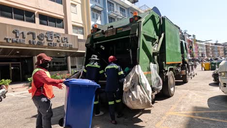 workers loading trash into garbage truck