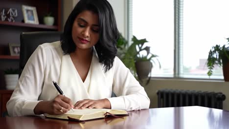 a professional woman engaged in thoughtful writing at her desk, showcasing dedication and focus in a serene office environment