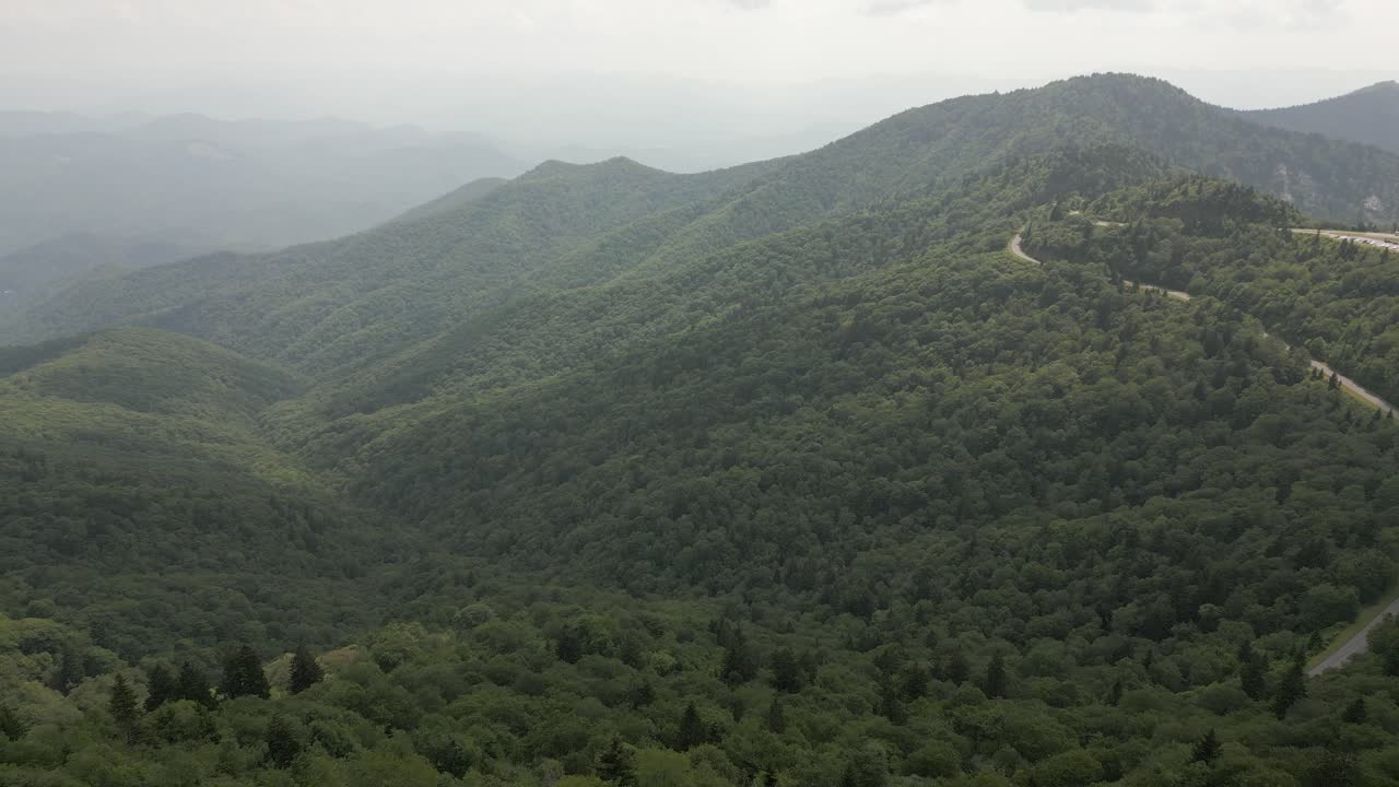 una vista aérea de la montaña llena de humo sobre los árboles del valle verde densamente boscosos