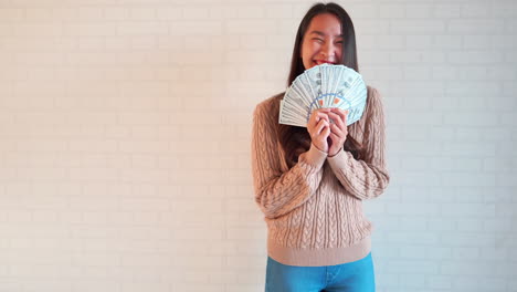 excited asian woman celebrating winning lots of money online in the lottery