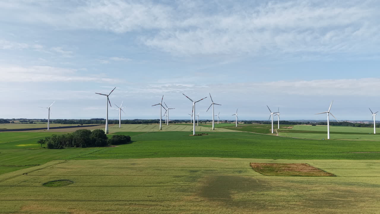 There are many wind turbines in the fields and they turn