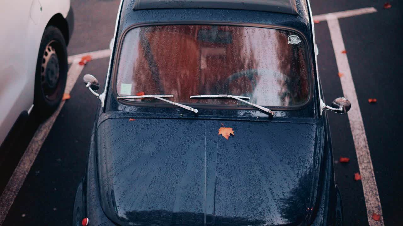 Cannes, France - October 20, 2025: Aerial view of a classic blue car covered in raindrops, parked in an urban lot
