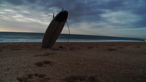 Stehendes-Surfbrett-Am-Sandstrand,-Meereswellen-Im-Hintergrund,-Exemplar-Oder-Titelraum