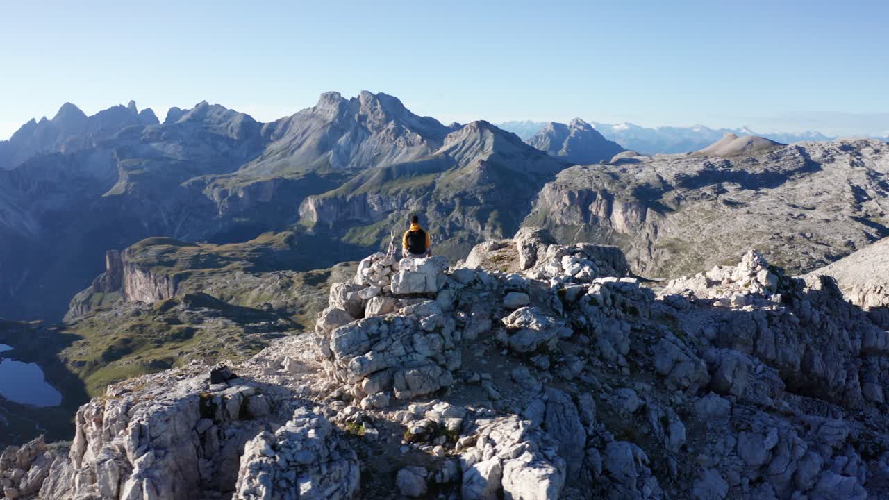 hombre sentado en la cima de la montaña y admirando la vista, el paisaje aéreo de los dolomitas