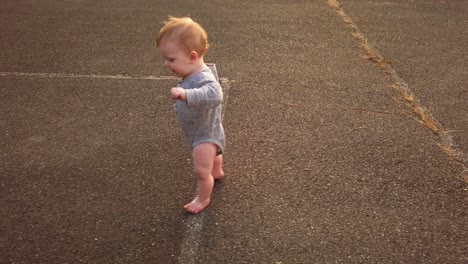 Happy-toddler-boy-takes-first-steps-unassisted-without-help-in-empty-schoolyard