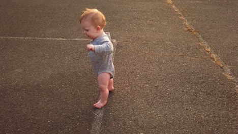 happy toddler boy takes first steps unassisted without help in empty schoolyard