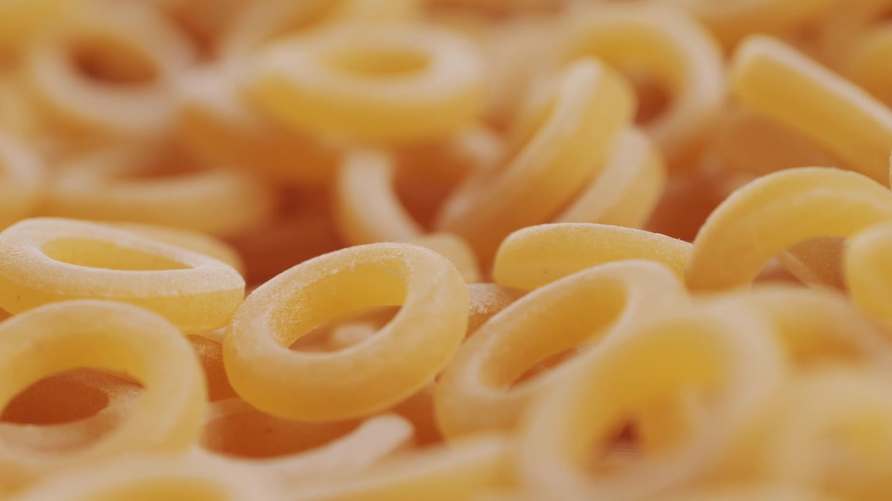 Pasta integrale biologica, maccheroni di semola di grano duro, penne rigate crude in una ciotola di legno. Filmato 4k di alta qualità