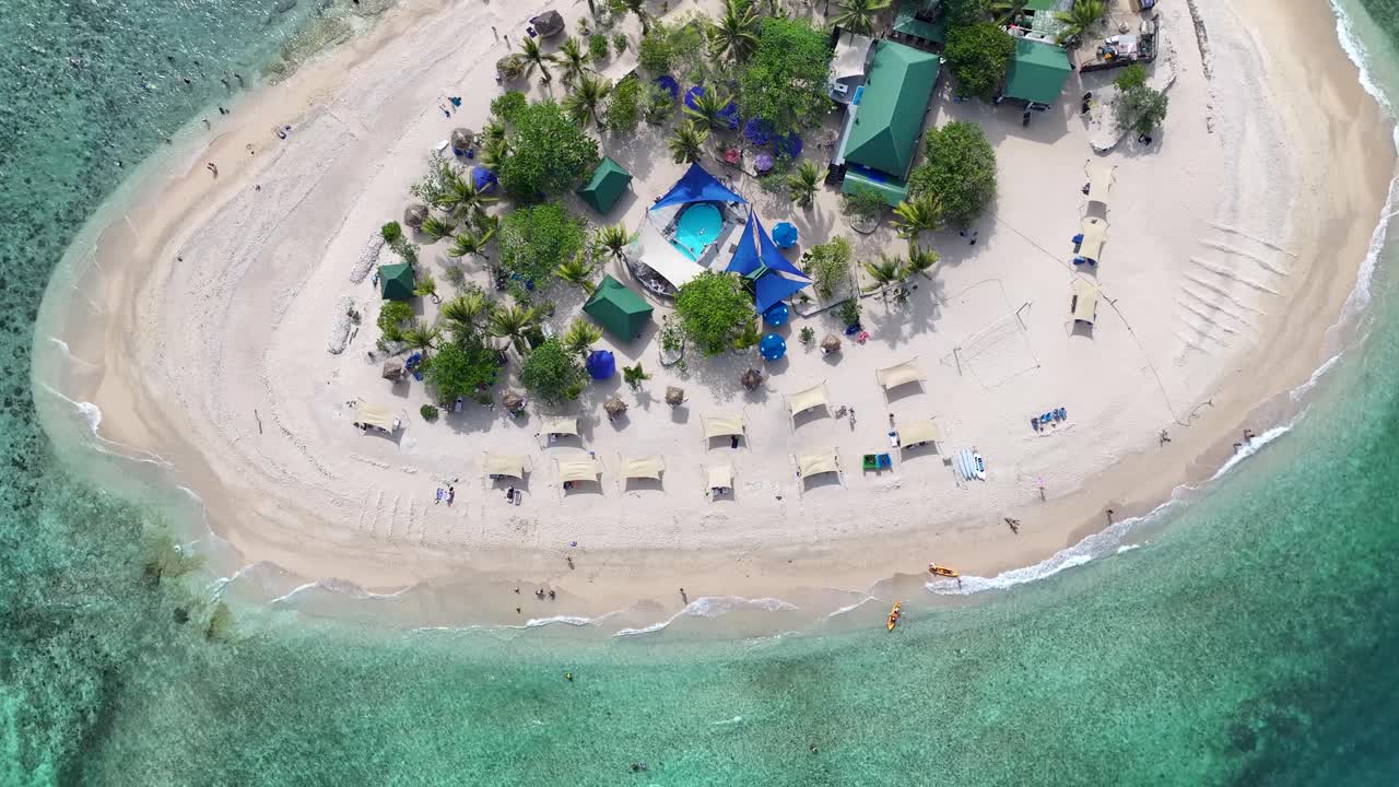 Drone view of small picturesque beach with sun beds in tiny island. Summer vacation Fiji.