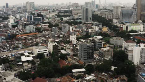 aerial birds eye shot of jakarta city with traffic on intersection in downtown during cloudy day, capital of indonesia