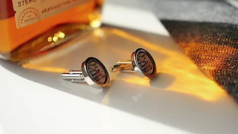 Custom-made-New-Jersey-map-cufflinks-in-the-orange-light-of-a-whiskey-bottle