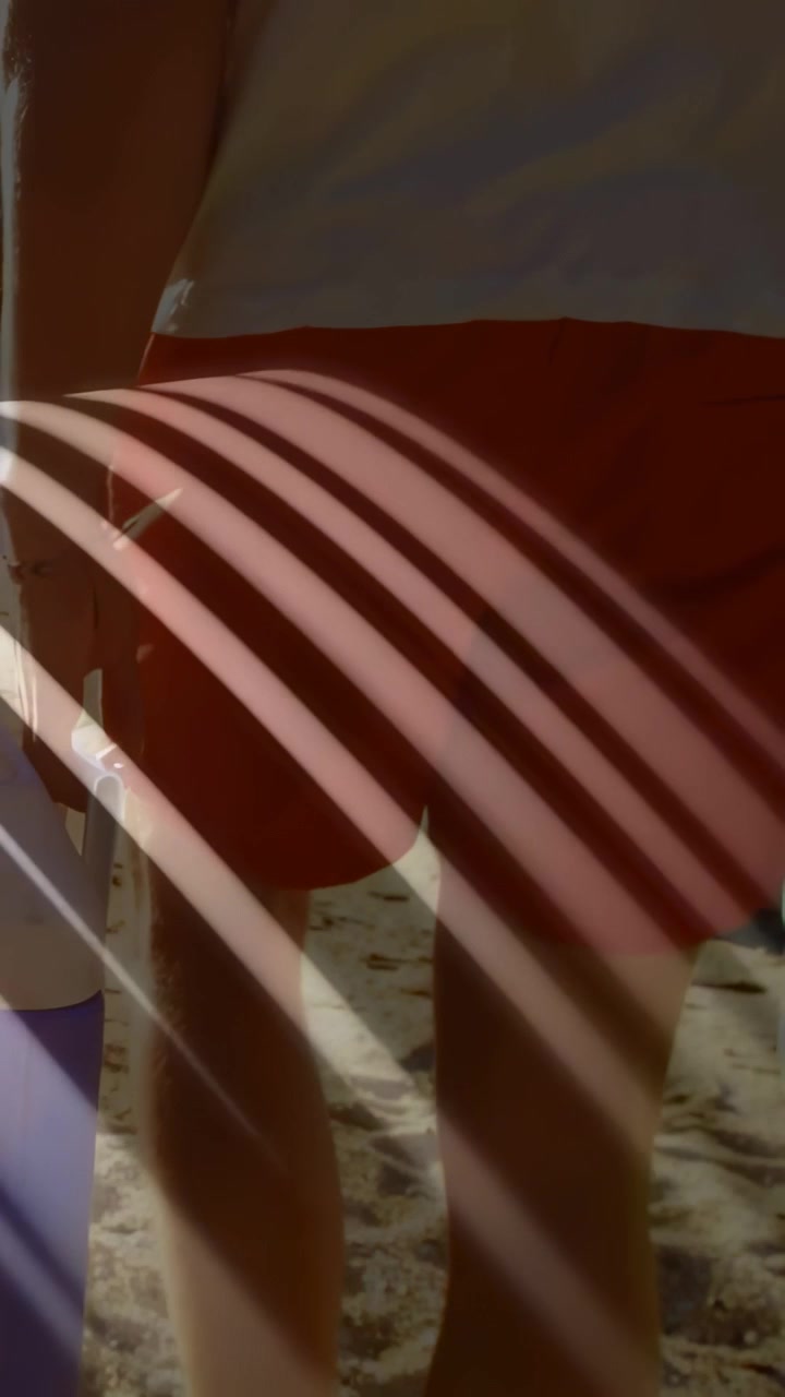 Vertical video: Cooler closeup with curved shadows, man entering right and walking toward shore