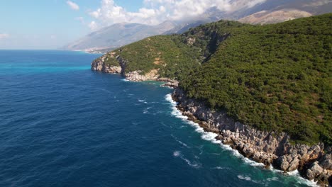 hermosa costa en la albania mediterránea, olas del mar salpicando rocas por las verdes colinas