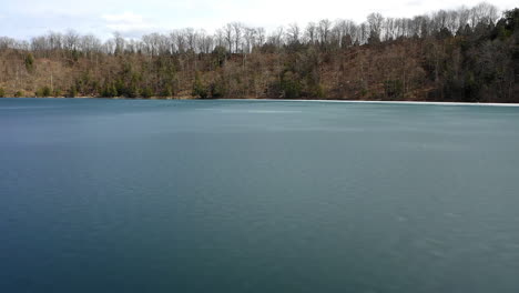 Fast-drone-pan-over-blue-green-lake-state-park-with-dead-forest-around-lake