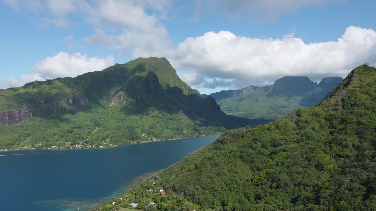 View of mountains and the ocean on a sunny day in a small green tropical pacific island from Magic Mountain, Moorea, French Polynesia.